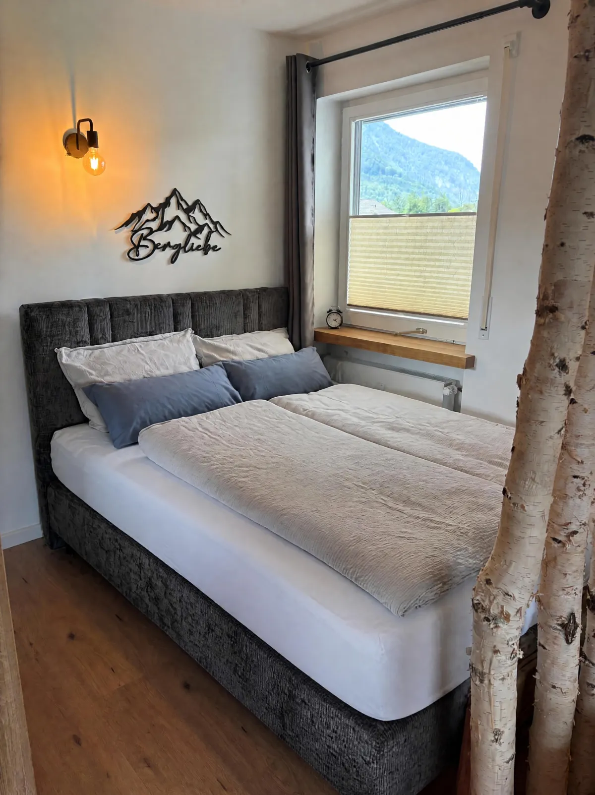 Neues Boxspringbett mit Bergliebe-Schriftzug und Bergblick aus dem Fenster